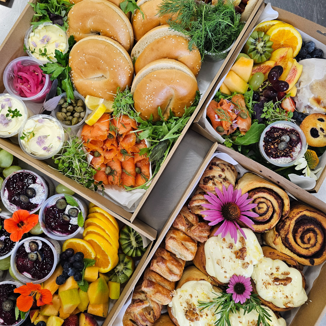 Assorted food platter with sandwiches, fruits, and pastries on a wooden board.