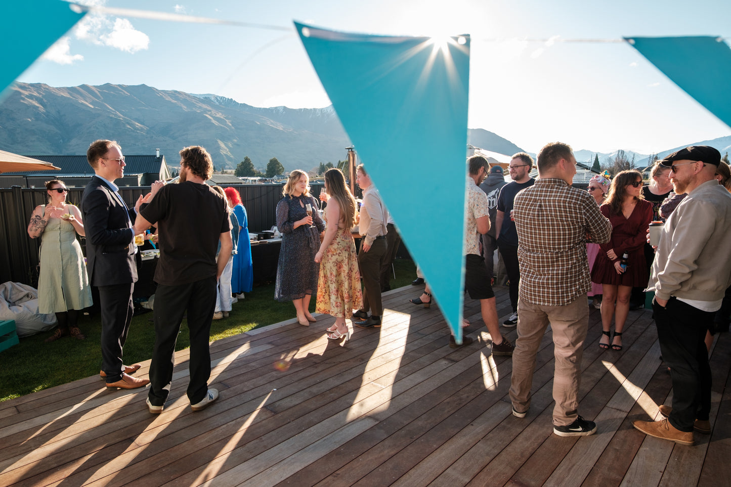 Group of people socializing on a wooden deck with mountains in the background