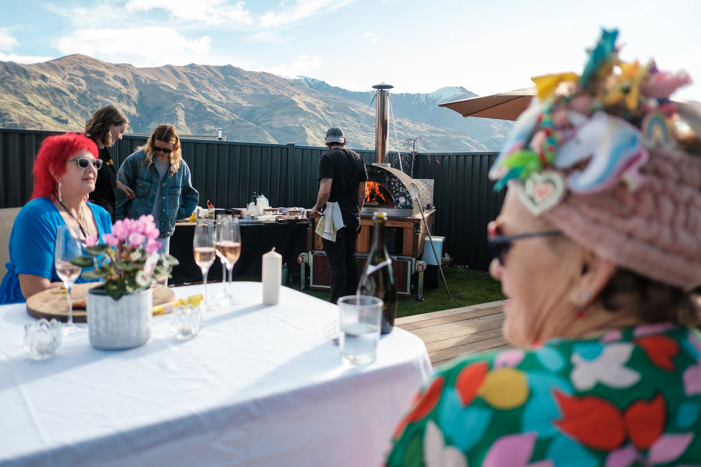 People enjoying a meal outdoors with mountains in the background