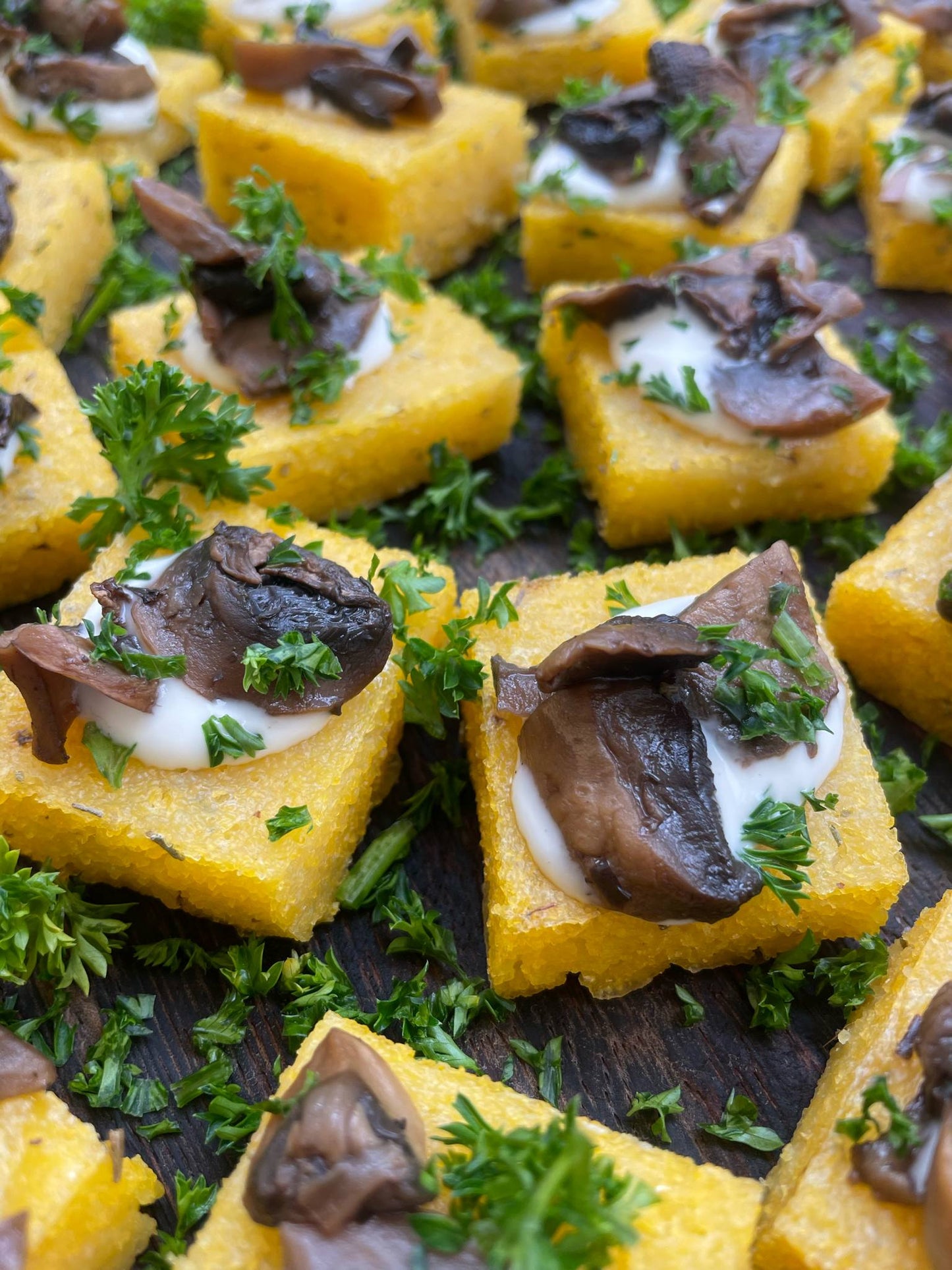Polenta squares with mushrooms and herbs on a wooden surface