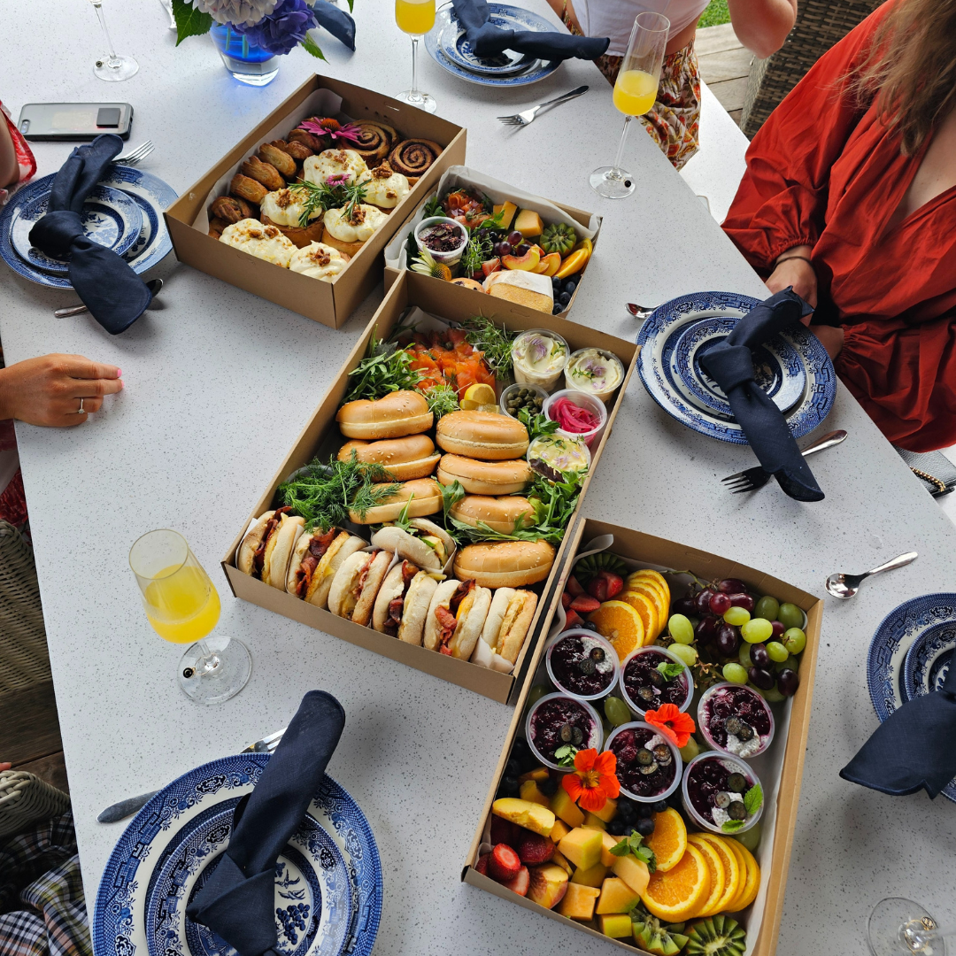 Table with boxes of food and people around, possibly at a party or gathering.