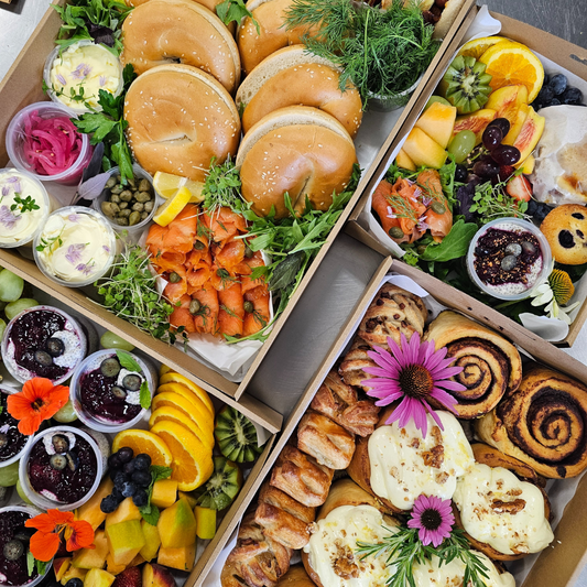 Assorted food platter with sandwiches, fruits, and pastries on a wooden board.