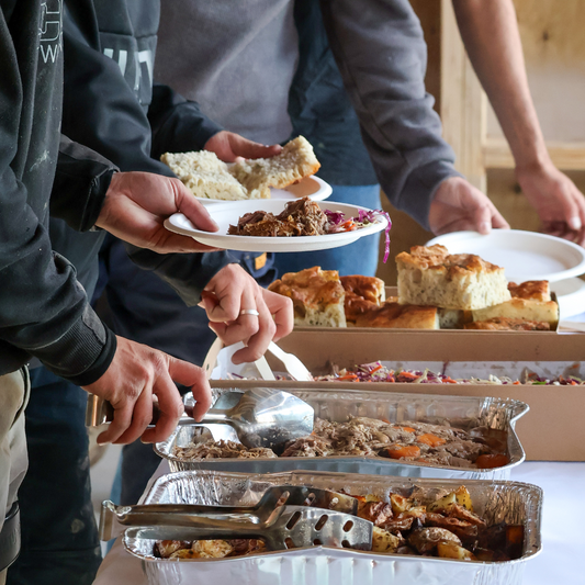 People serving themselves food from a buffet table with various dishes.